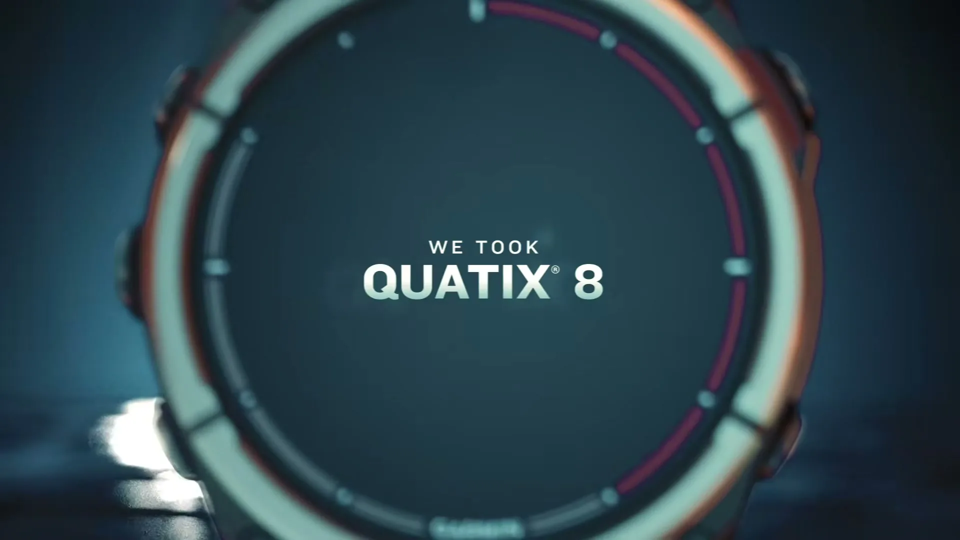 A close-up shot of a Garmin Quatix 8 smartwatch with text "WE TOOK QUATIX® 8" on its screen, in a dark, moody setting.