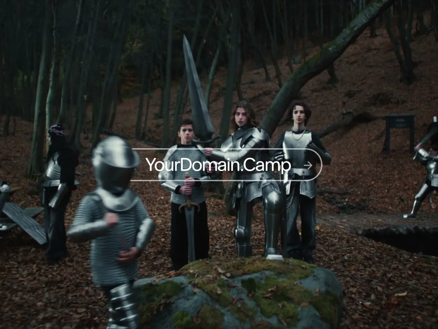 A group of young people dressed in medieval knight armor stand in a forest as a search bar for "YourDomain.Camp" appears on screen.