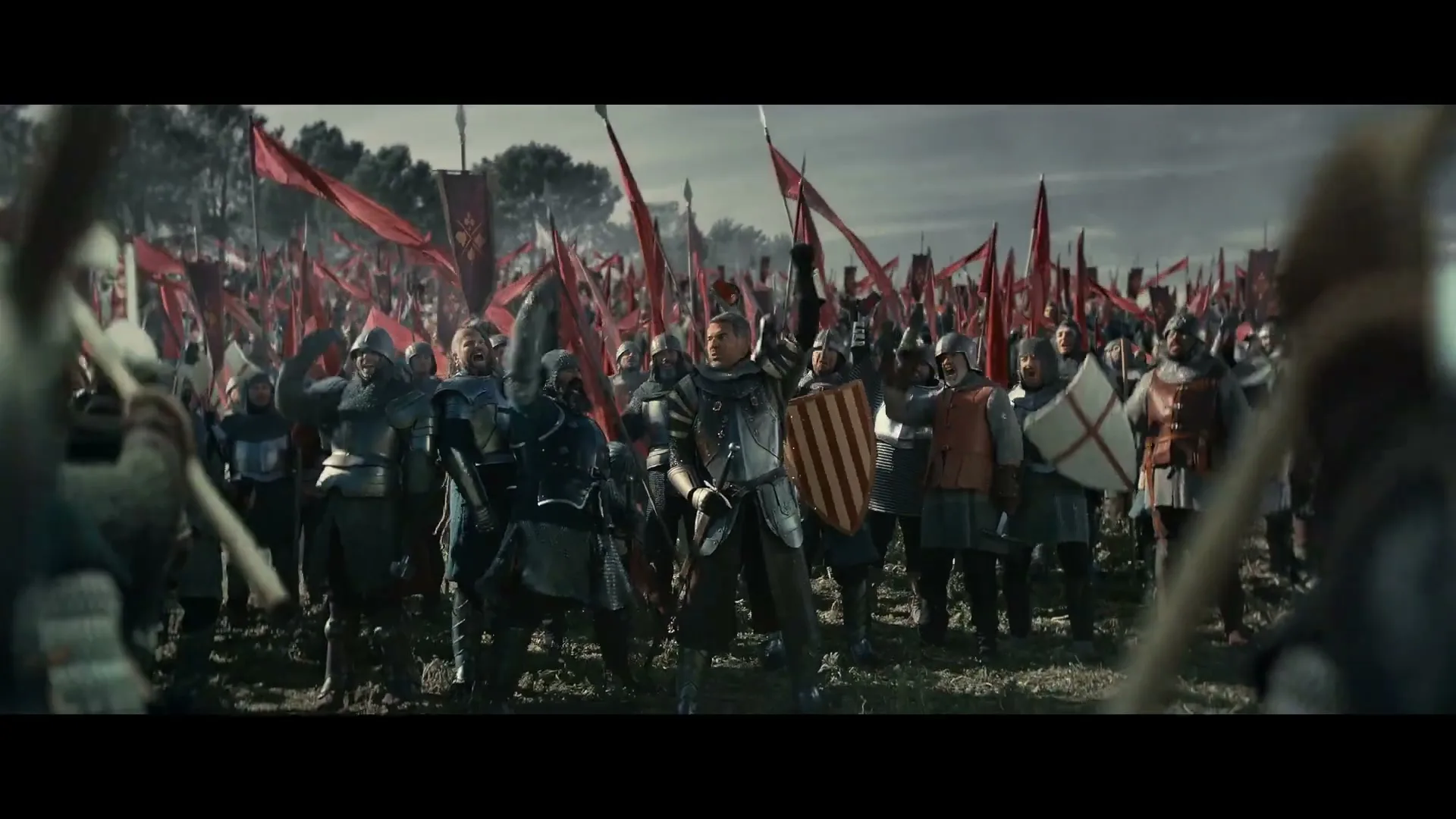 A medieval general in full armor raises his sword, rallying his army of knights and soldiers on a battlefield under a dramatic sky.