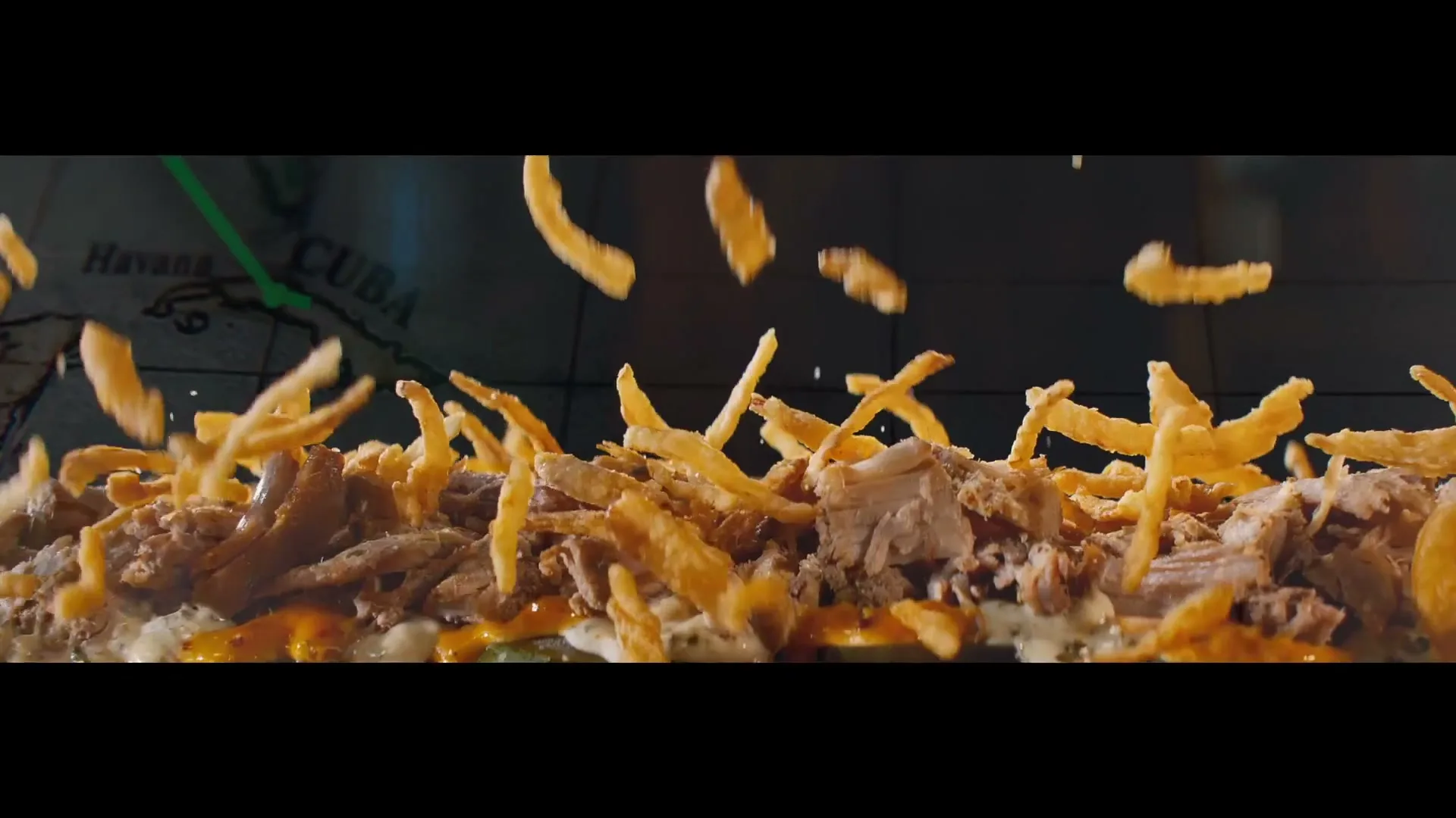 Crispy fried onions fall onto a Subway sandwich filled with pulled pork and sauce, against a map background.