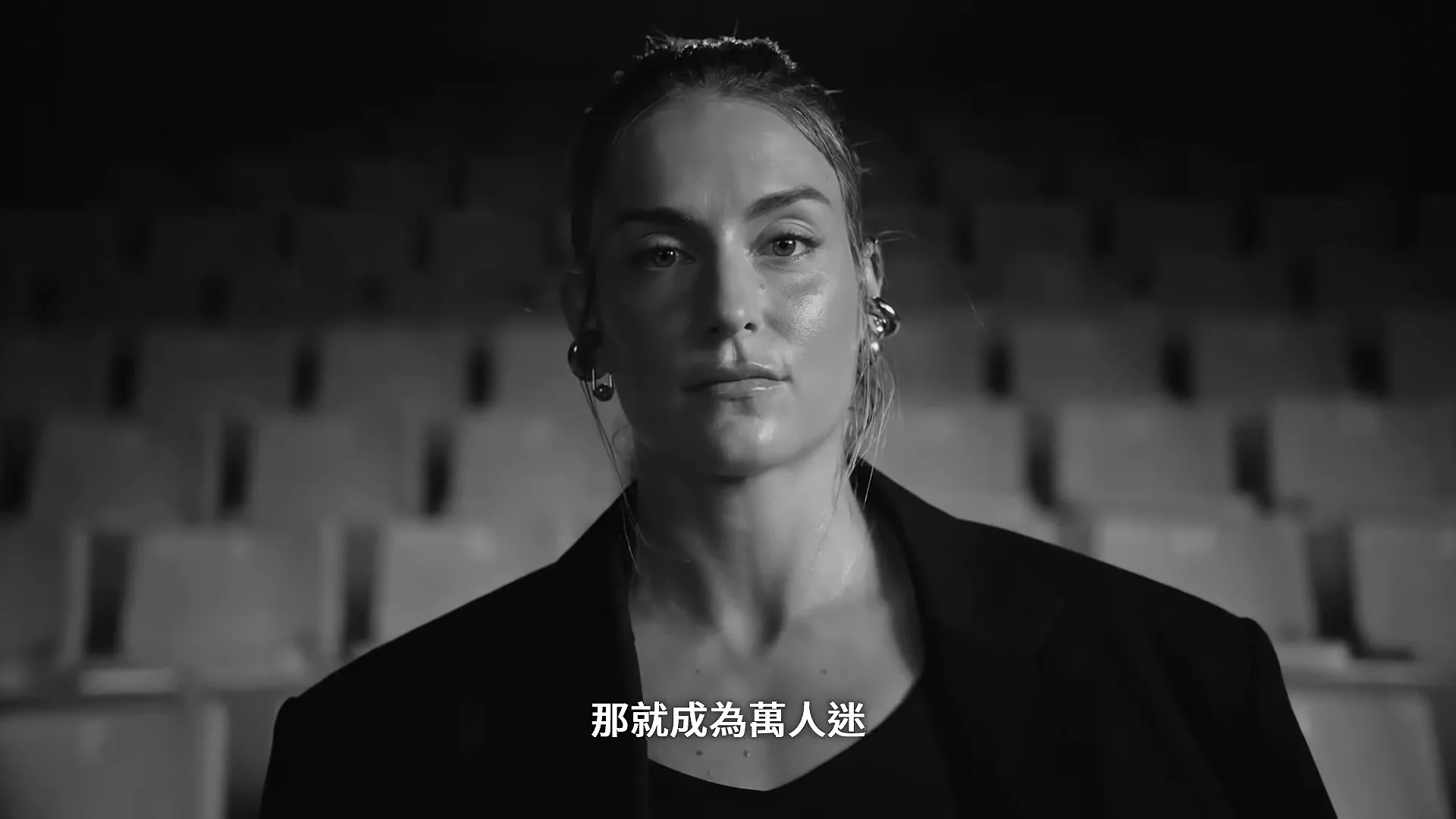 A female athlete in a black blazer looks directly at the camera in a stadium, with Chinese text overlayed.