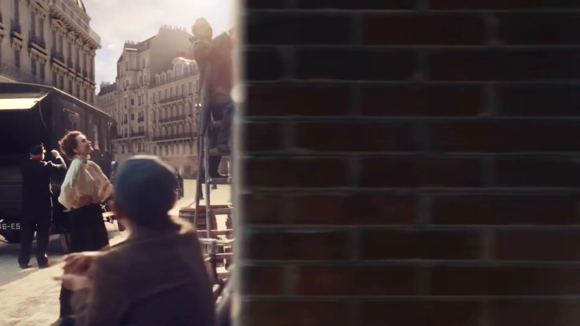 A man on a ladder puts up a sign for "Pierre & Rose" above a grocery store, while a woman and a boy watch, then the camera moves inside to show the couple arranging produce.