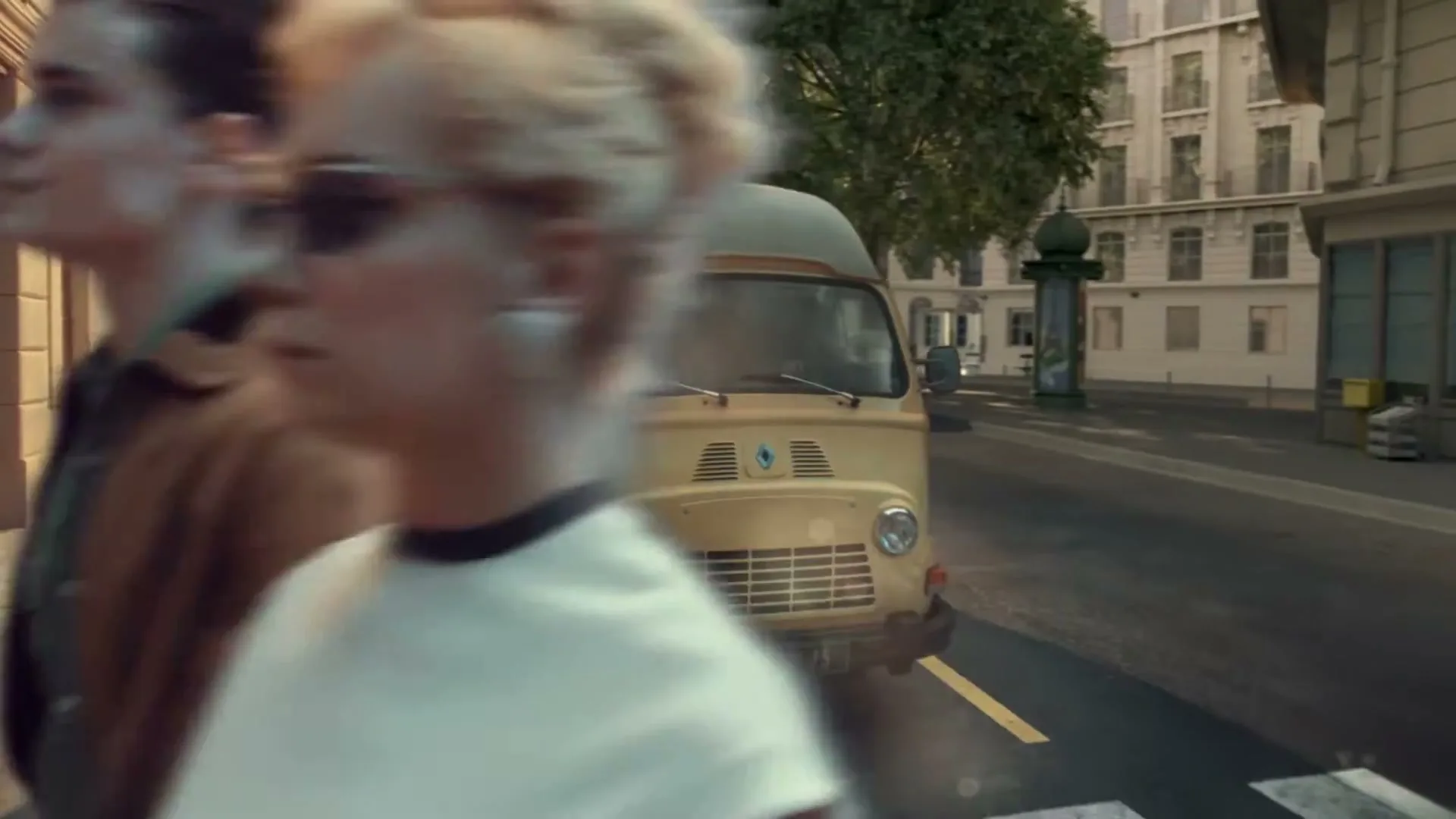 A yellow Renault van is parked on a street in front of a record store, while people walk and ride a moped past it.