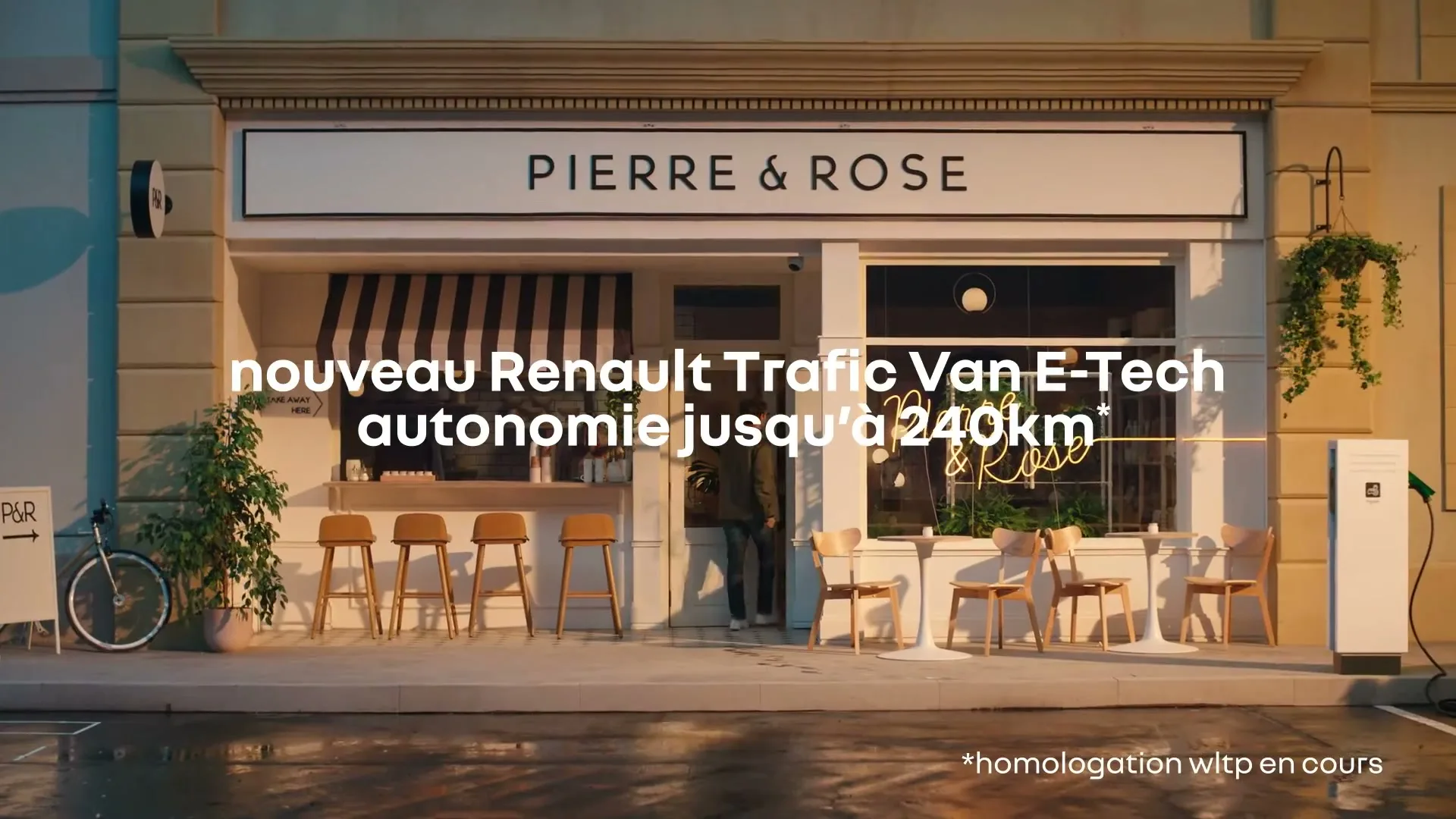 A person in a green jacket walks into a cafe named Pierre & Rose, with outdoor seating and a bicycle parked outside, on a wet street.