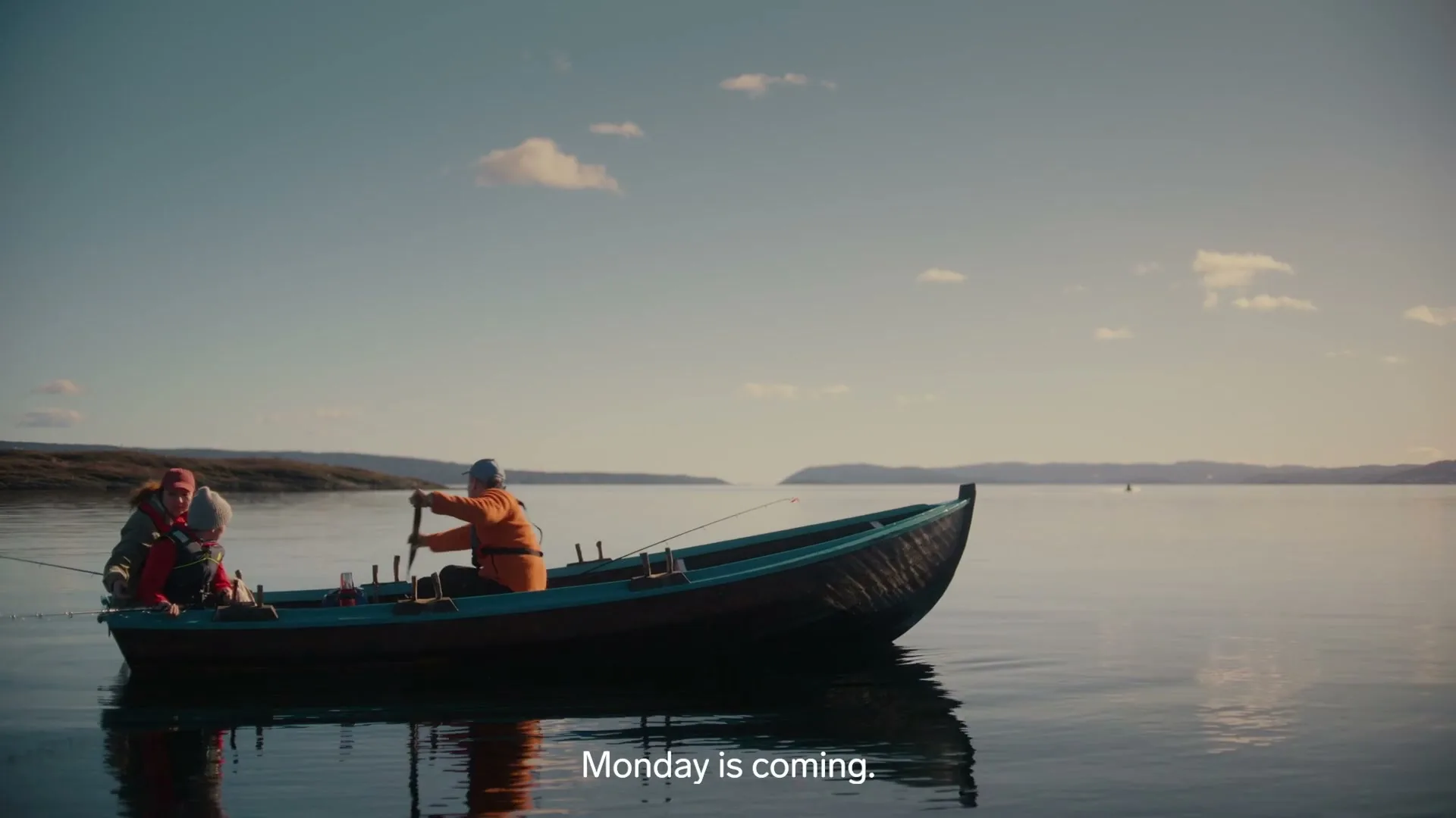 Two people in a small boat are fishing on a calm lake with land in the background under a clear sky.