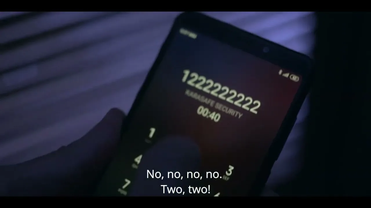 A person's hand holds a smartphone, attempting to dial a number on the screen, in a dimly lit interior.