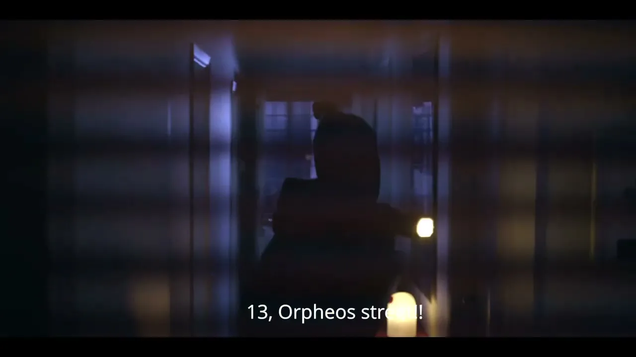 A person in dark clothing and a balaclava holds a flashlight, looking through a window into a dark room at night.