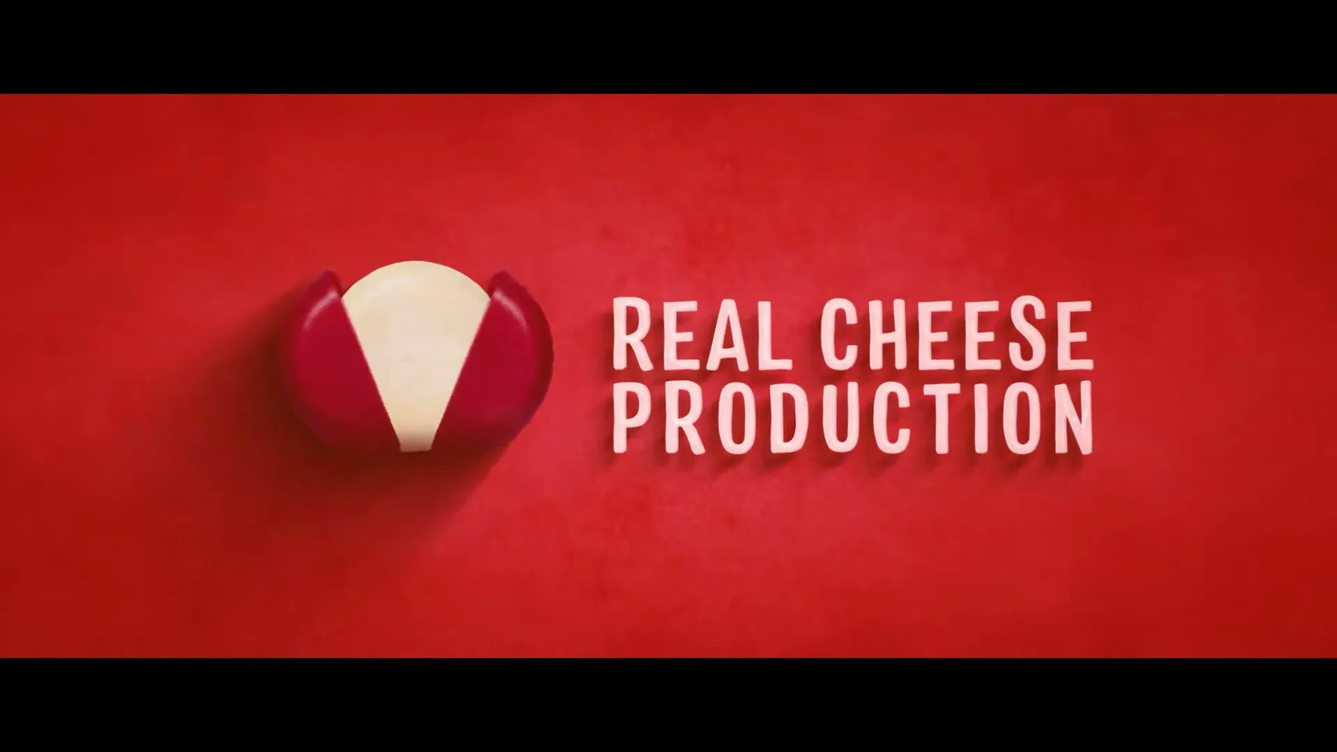 A Babybel cheese wheel, still in its red wax, is shown on a red background, then the wax peels open to reveal the cheese inside, next to the words "REAL CHEESE PRODUCTION."