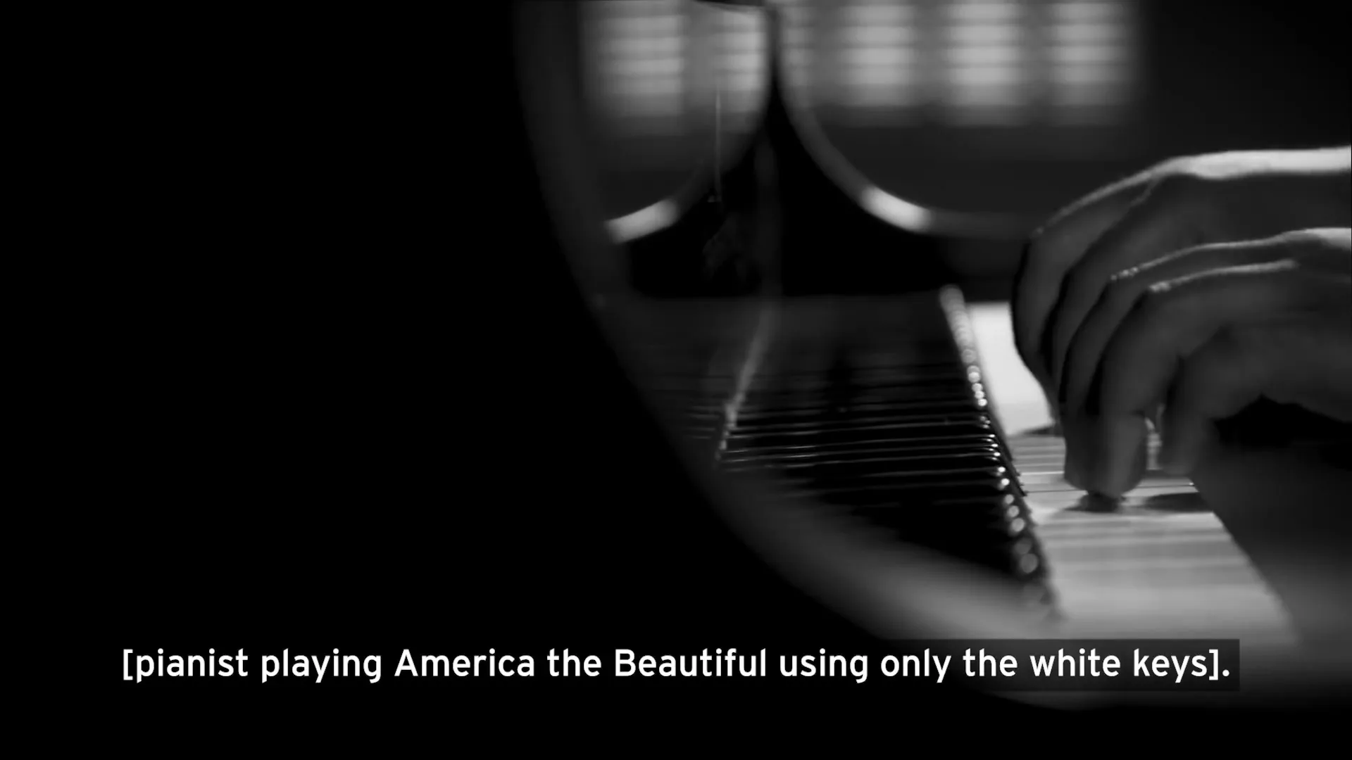 A close-up shot of a person's hands playing a piano, with the keys and part of the piano visible in a dimly lit room.