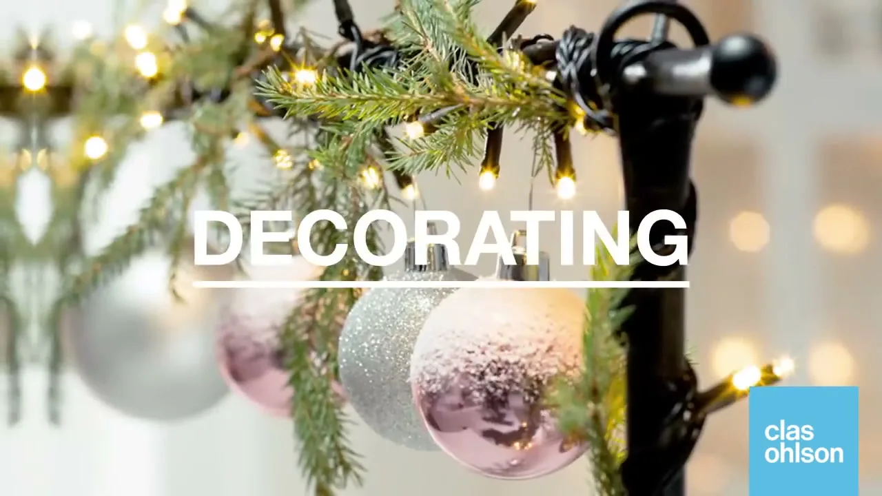 A close-up shot shows Christmas ornaments hanging from a branch with fairy lights, with the word "DECORATING" on screen.