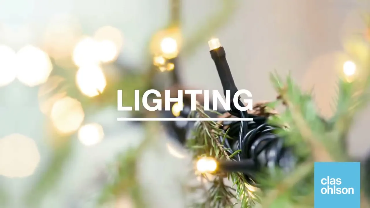 A close-up shot of warm white Christmas lights on a green Christmas tree, with the word "LIGHTING" on screen.