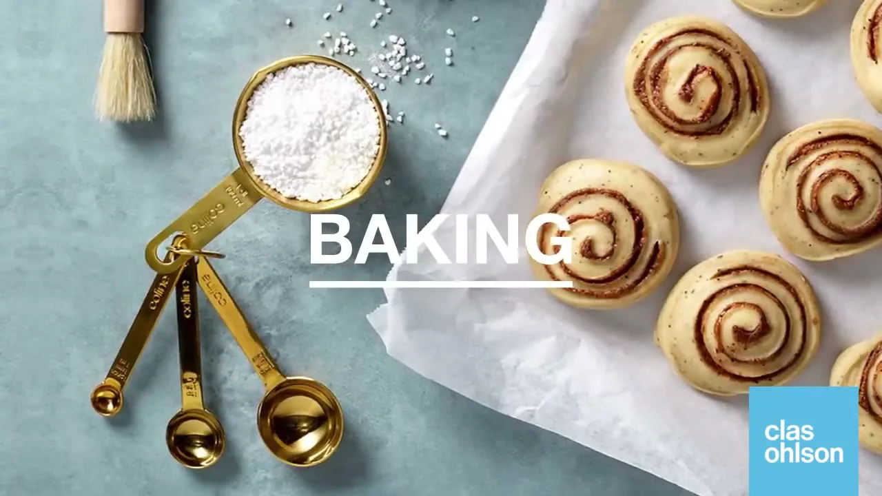 A top-down shot shows golden measuring spoons with flour and cinnamon rolls on parchment paper, with the word "BAKING" on screen.