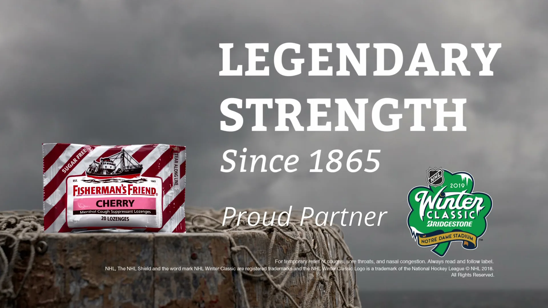 A pack of Fisherman's Friend Cherry lozenges sits on a weathered wooden post with fishing net, against a grey sky and ocean, with text overlay.