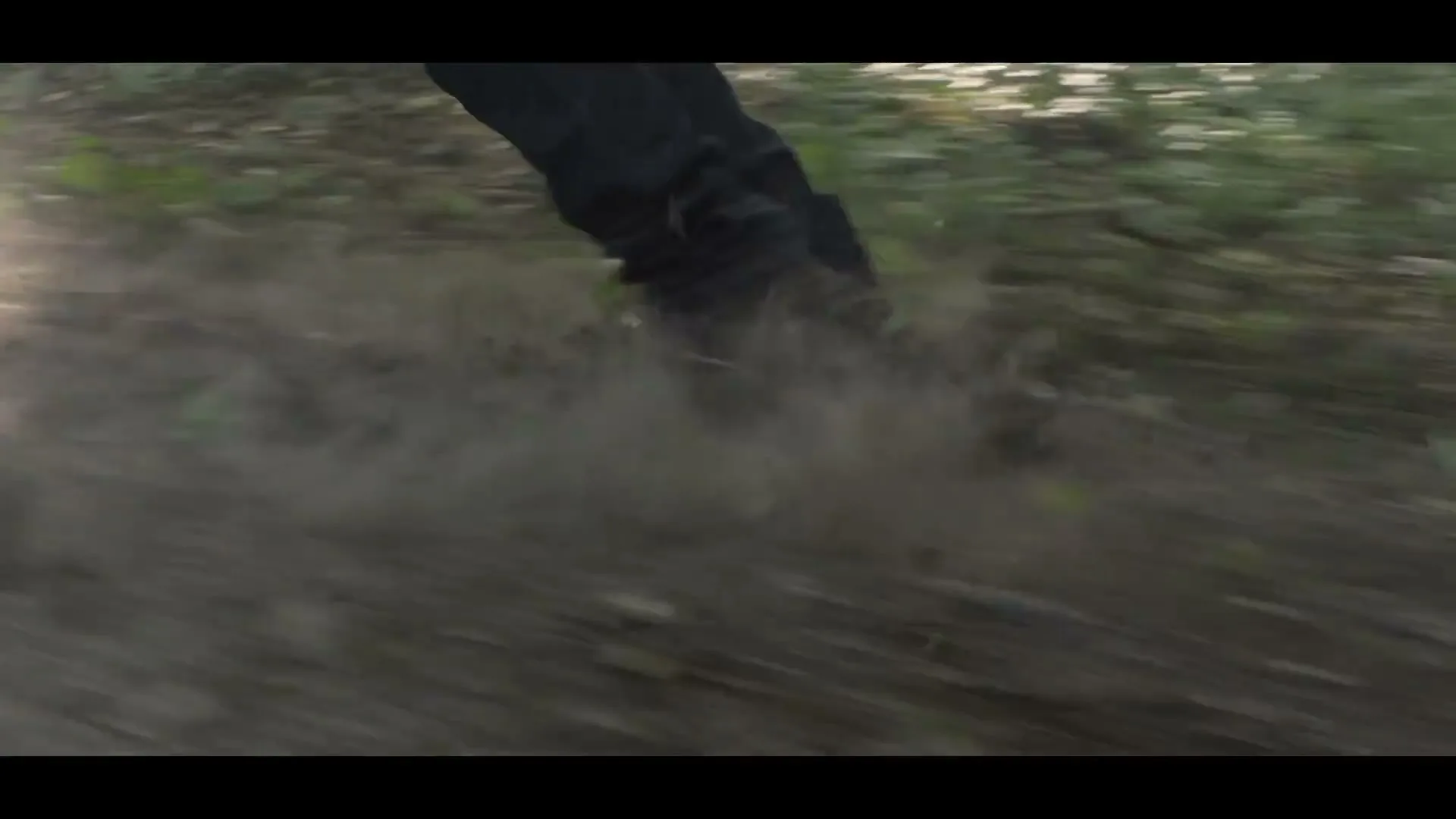 A man in a brown shirt and green vest is seen from the chest up, with a shocked expression, as he is pulled backward through a forest.