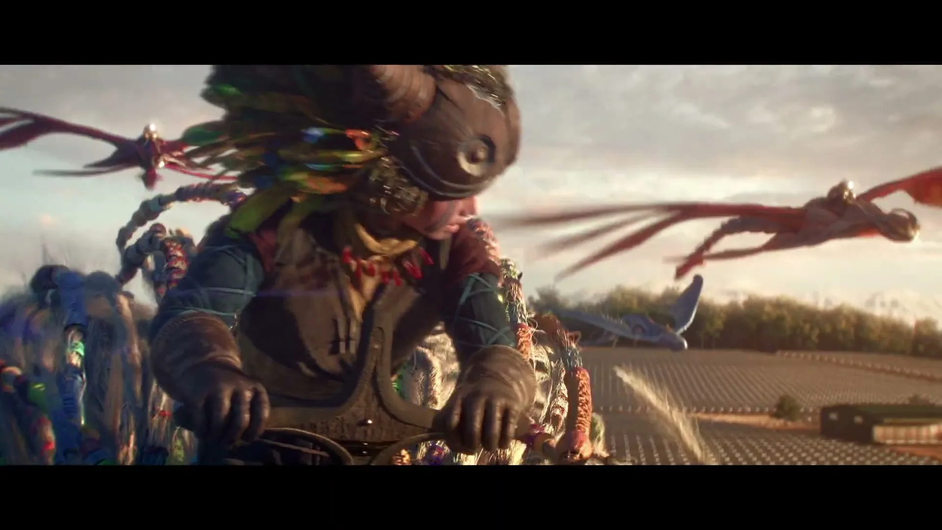 A young person in a feathered helmet and tribal paint rides a fantastical vehicle across a field, with dragon-like creatures flying alongside.