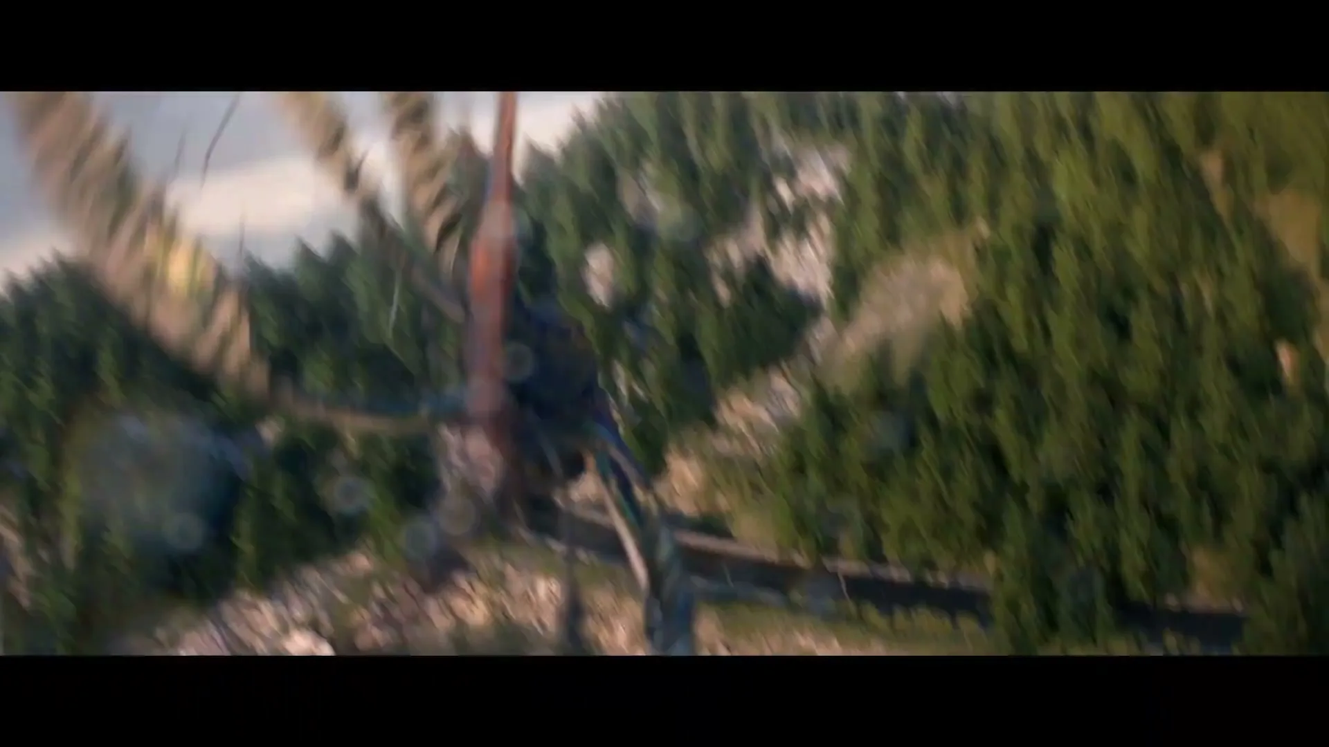 Two pterodactyl-like creatures fly over a river and forest, approaching a tunnel in a mountain, in a wide shot.