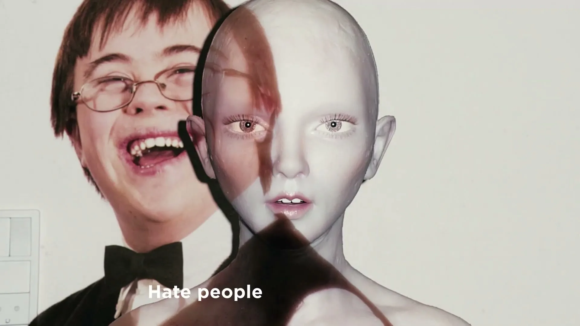 A white mannequin head with a brown stripe on its face is in the foreground, with a laughing boy in glasses and a bow tie projected behind it.