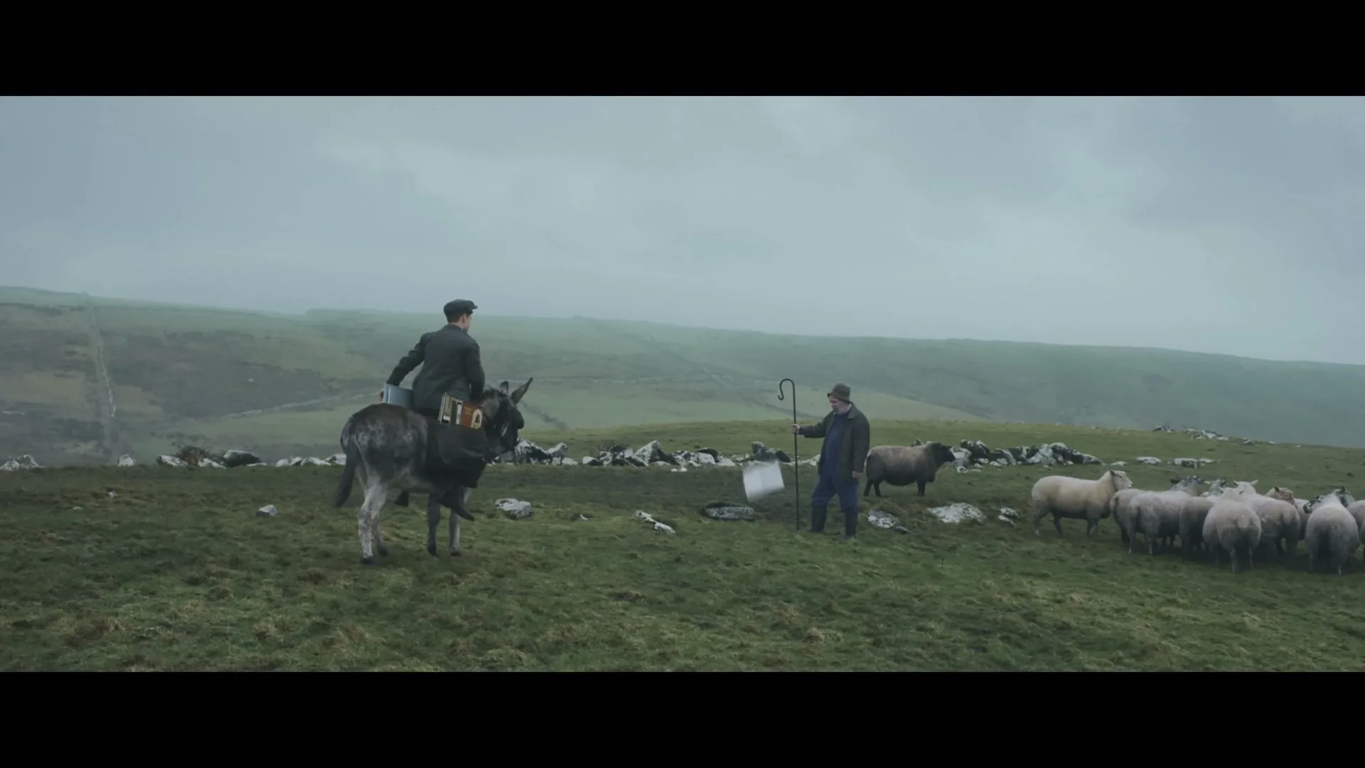 A man on a donkey and a shepherd with his flock watch a white cube descend from the sky onto a grassy hill.