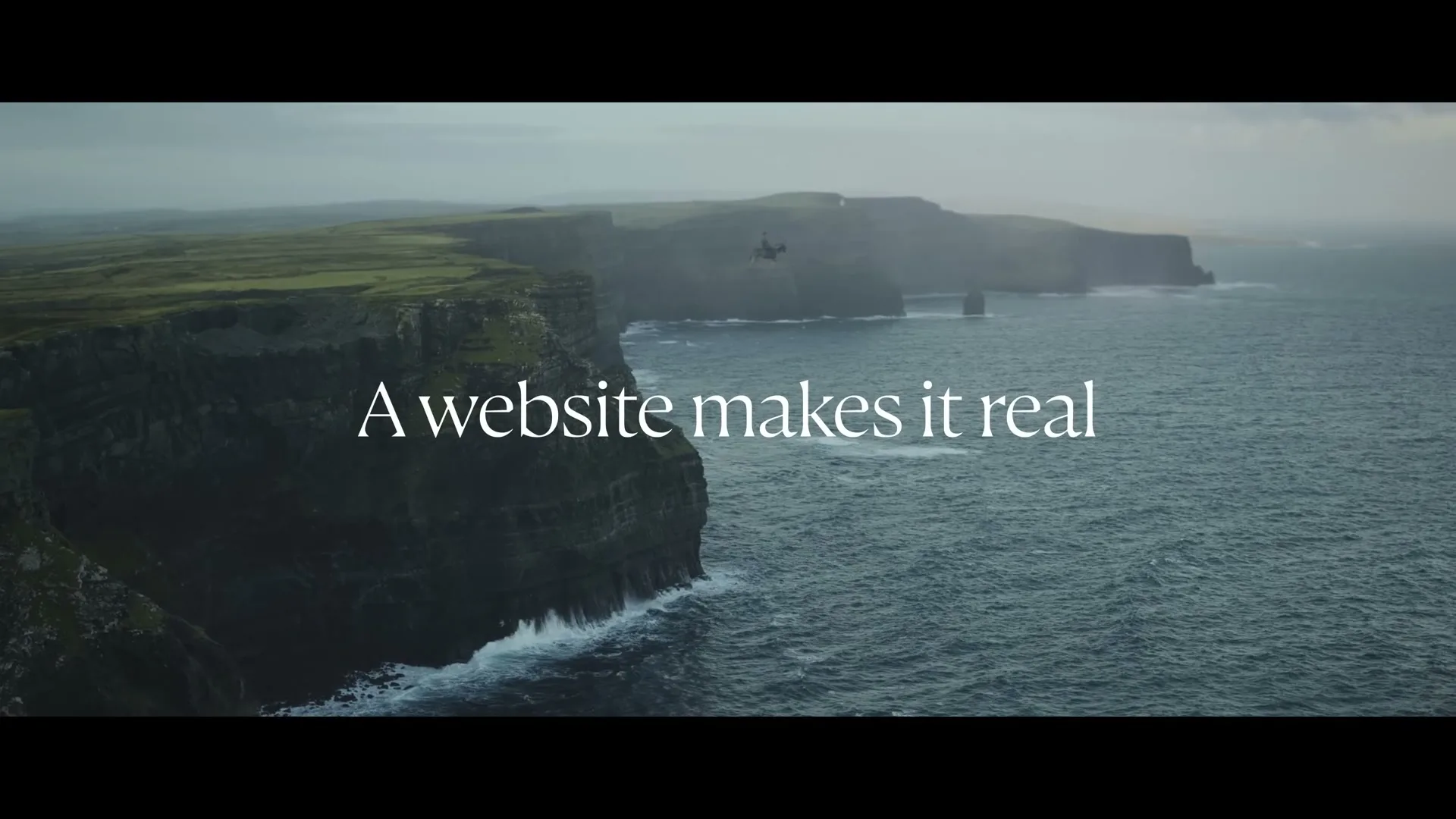 A wide shot of a helicopter flying over the Cliffs of Moher in Ireland, with the ocean waves crashing against the cliffs.