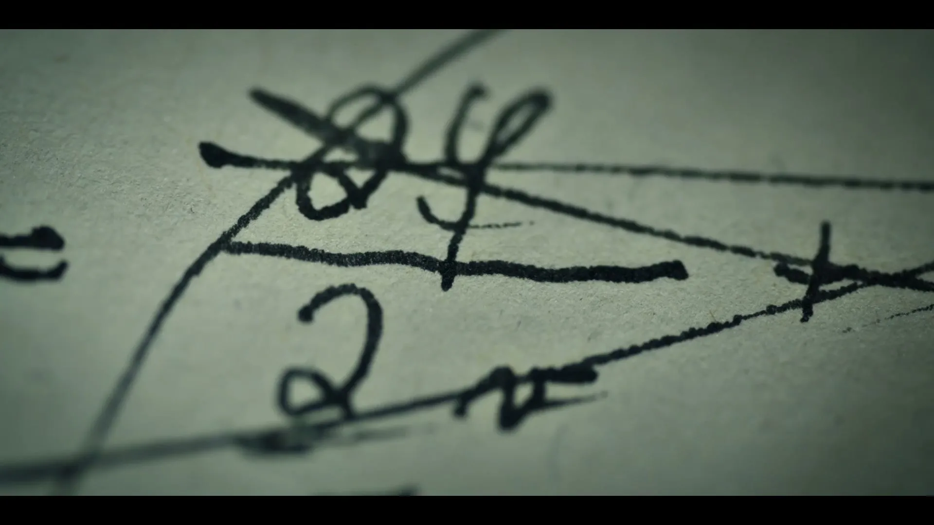 A close-up shot of handwritten mathematical equations on a piece of paper, with a dark, moody lighting.
