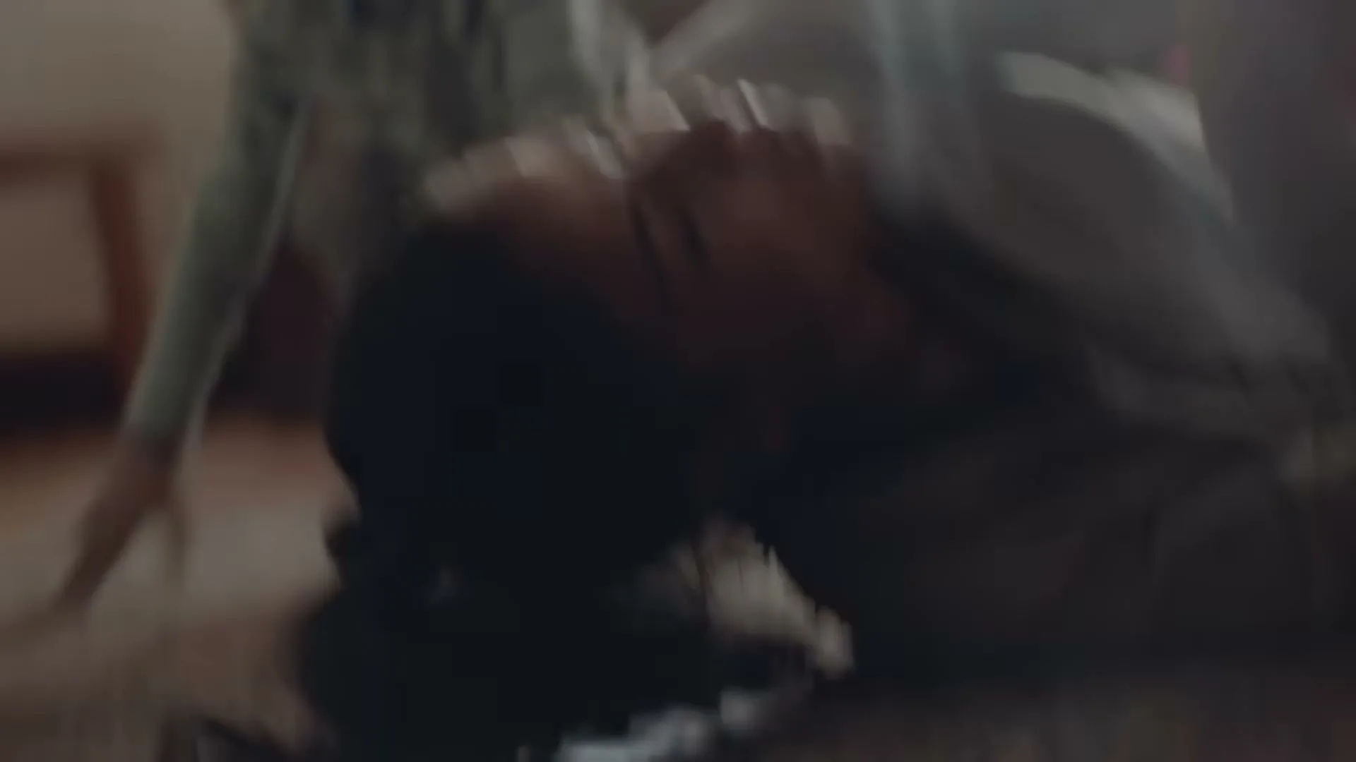 A woman with dark hair and a child are doing push-ups on the floor, then the woman collapses onto her back, looking exhausted in a living room.