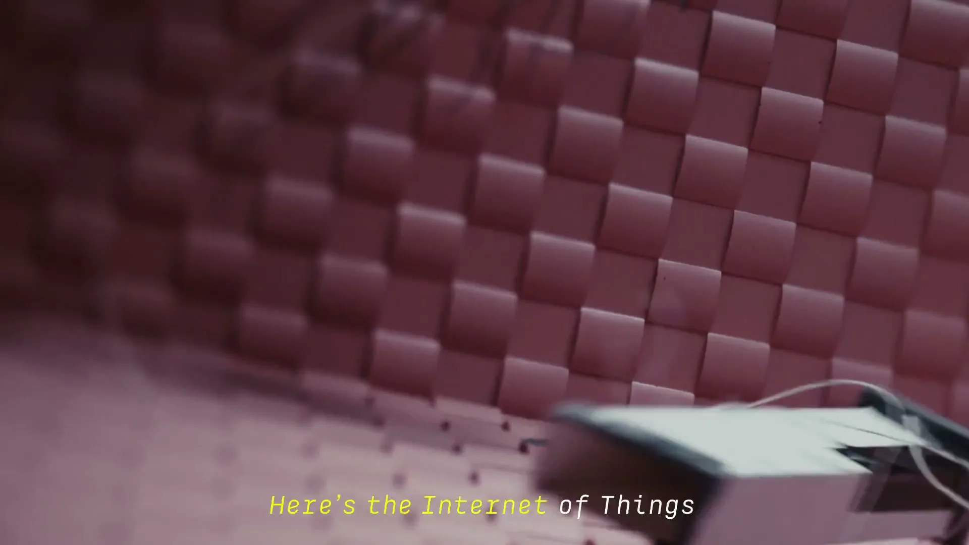 A black box with wires falls and bounces on a pink textured floor, then a puppet with red hair and wires attached to it falls into frame.