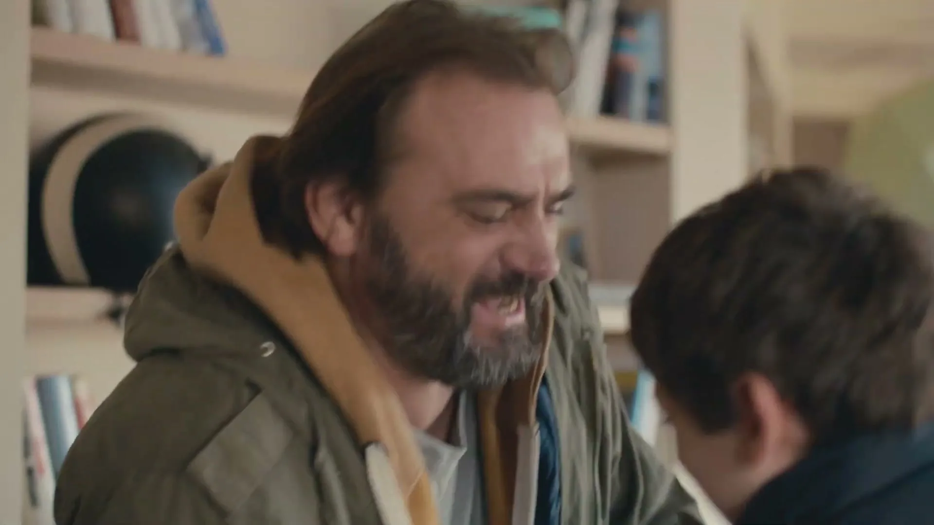 A father and son play-fight and laugh together in a cozy living room, sharing a moment of joy and connection.