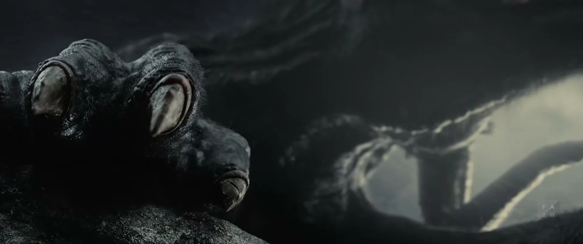 A dark, monstrous creature's claw with large, round eyes is shown in a close-up, with more of its shadowy body in the background.