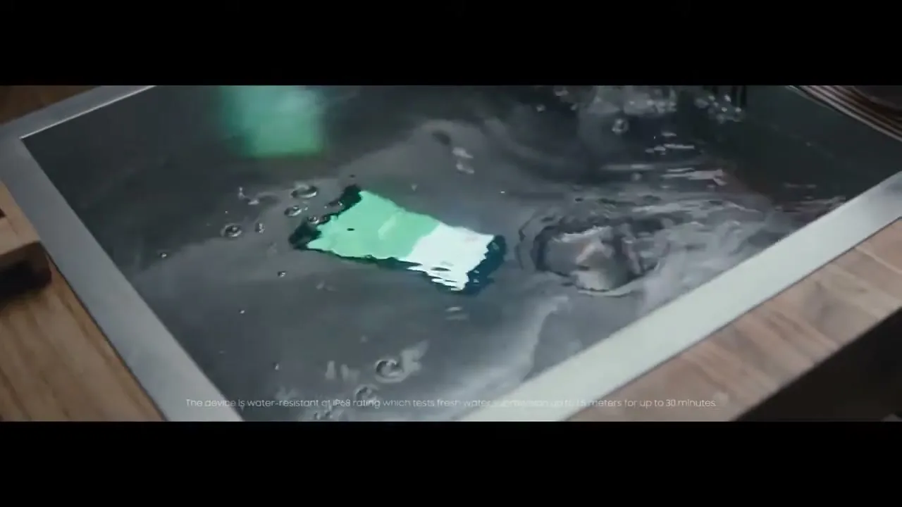 A green and white smartphone is submerged in a kitchen sink full of water, demonstrating its water resistance.