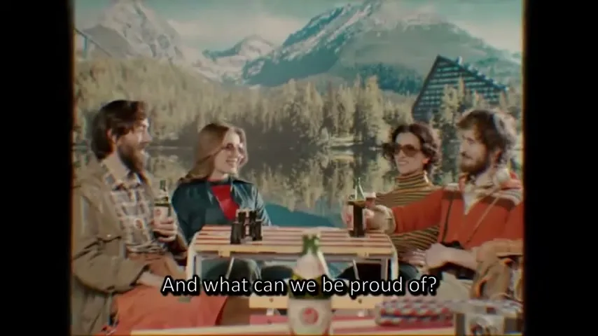 A group of four friends, two men and two women, are sitting around a picnic table, drinking beer, with a scenic mountain and lake backdrop.
