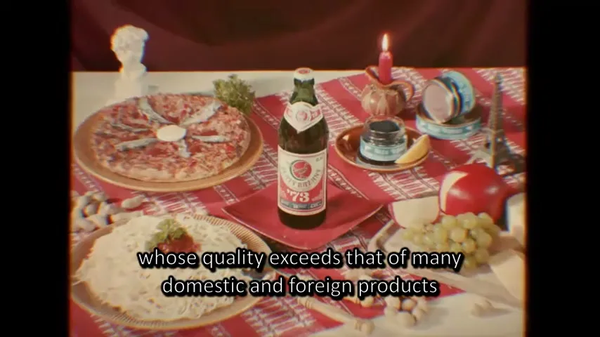 A bottle of Zlaty Bazant 73 beer stands on a red patterned tablecloth, surrounded by various dishes and decorative items, with text overlayed.