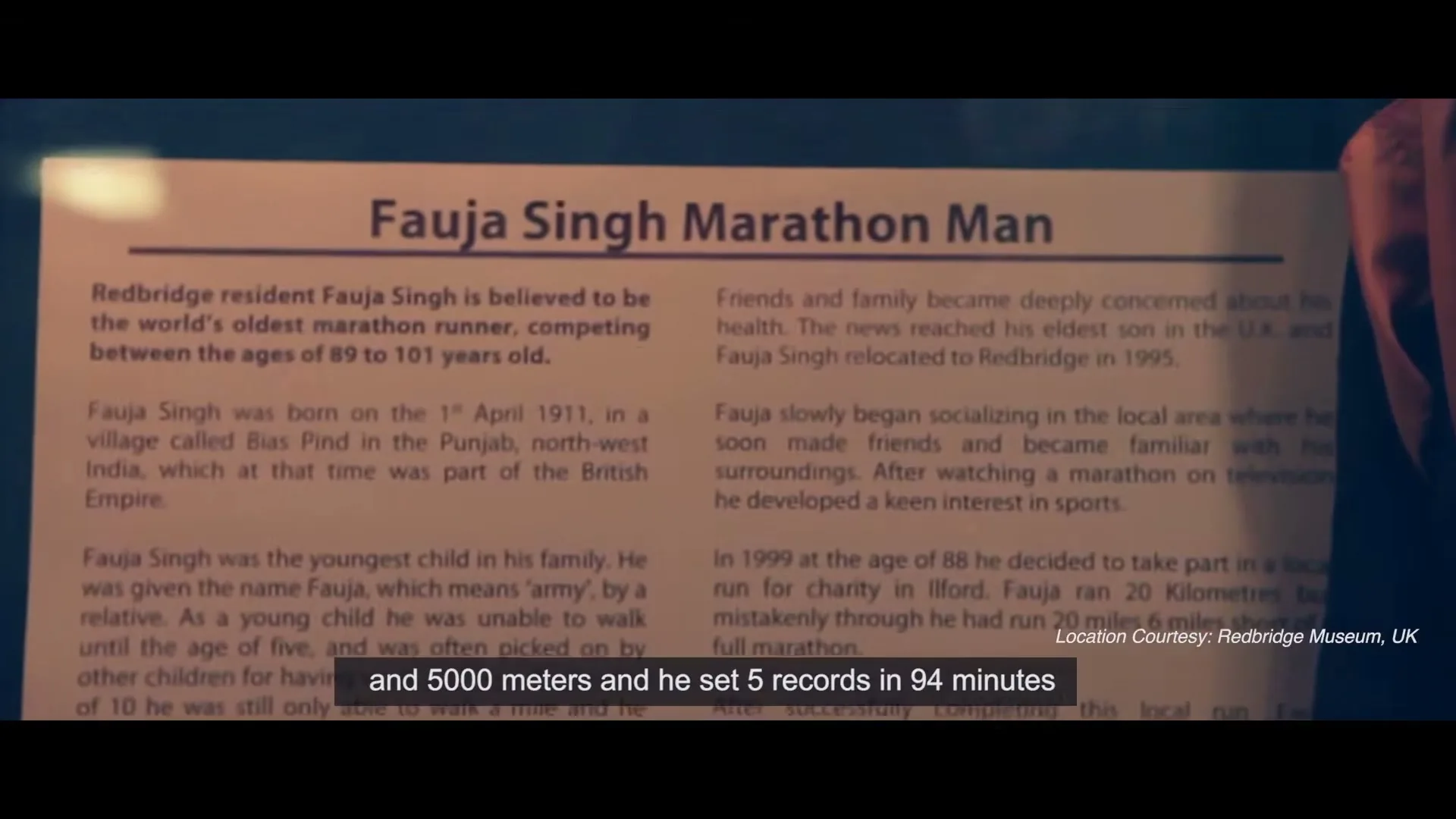 A close-up shot of a framed informational text about Fauja Singh, the world's oldest marathon runner, displayed in a museum.