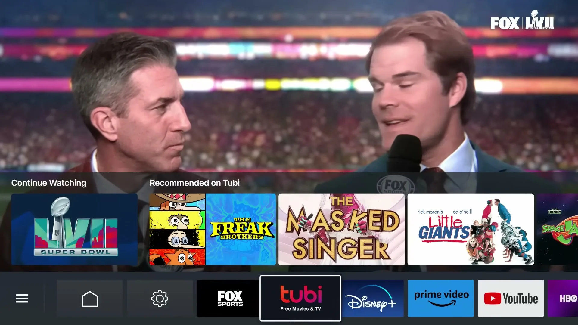 Two male sports commentators are seen on a TV screen, with a Tubi interface overlaying the bottom half, showing various streaming options.