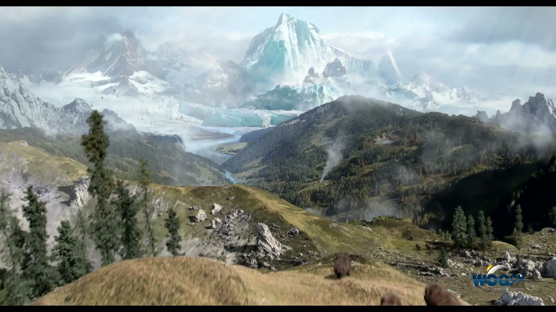 A herd of woolly mammoths stampedes over a grassy hill towards a valley with a river and snow-capped mountains in the background.