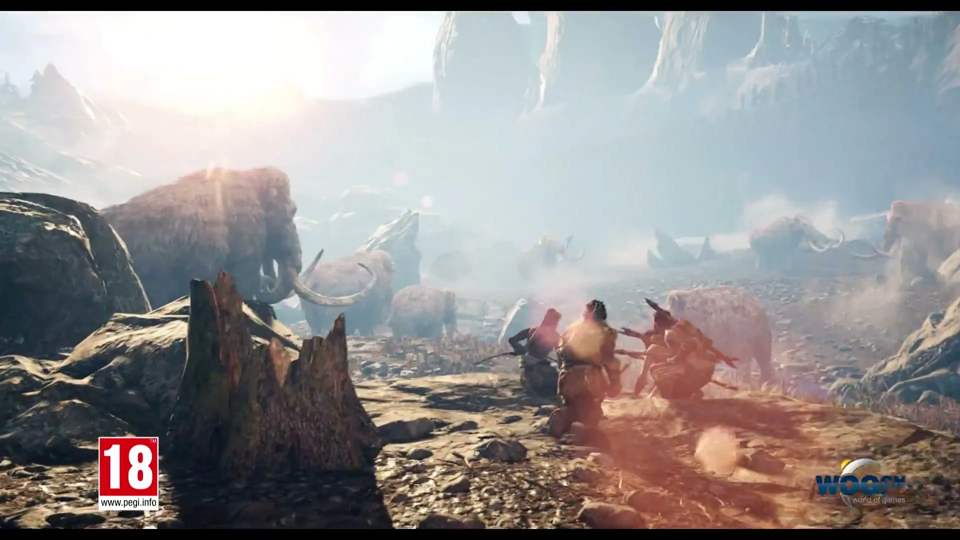 A group of primitive hunters with spears run across a rocky, dusty landscape with mammoths in the background under a bright sky.
