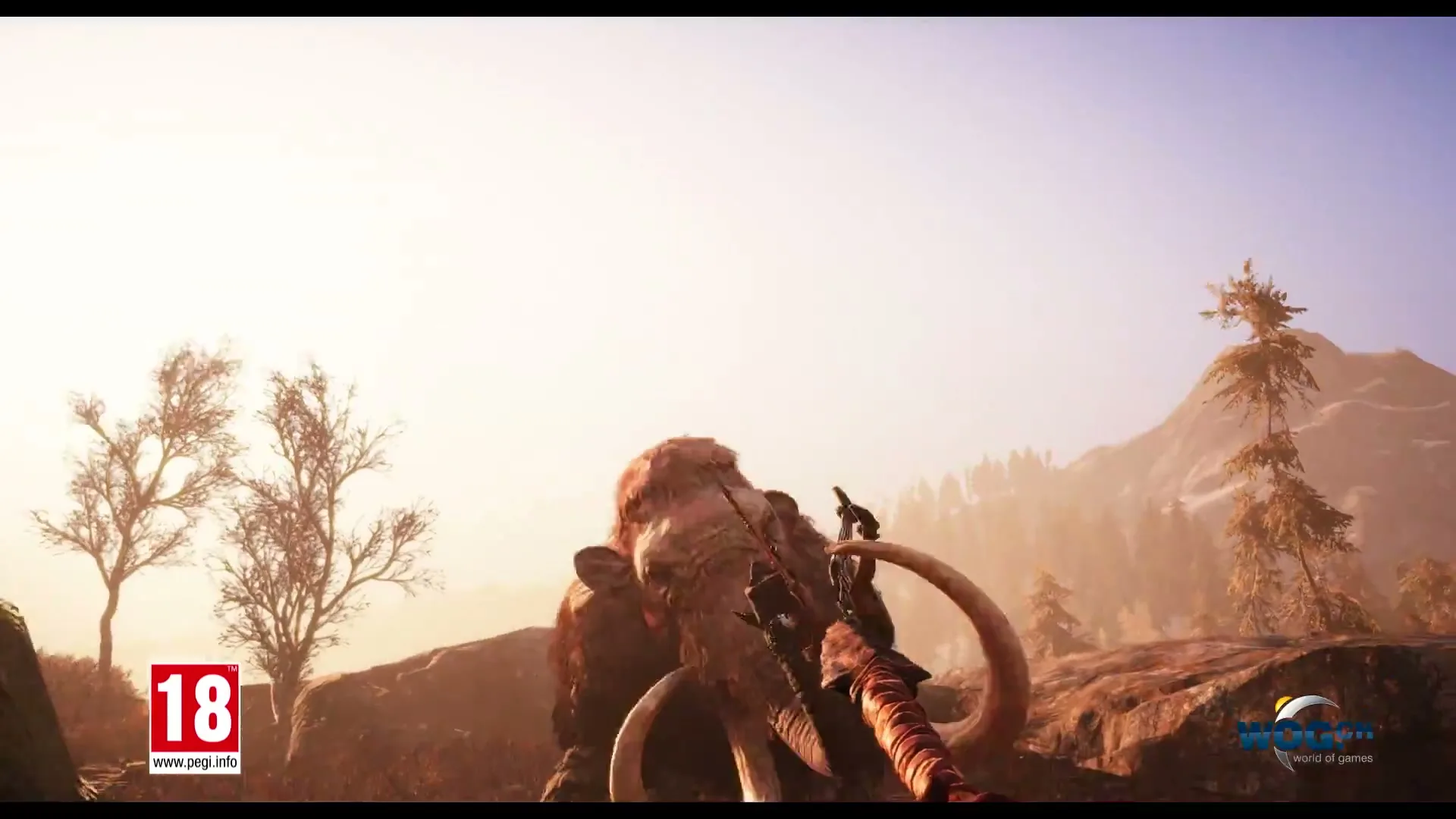A large, hairy mammoth with huge tusks rears up on its hind legs, with a person on its back, in a prehistoric landscape.