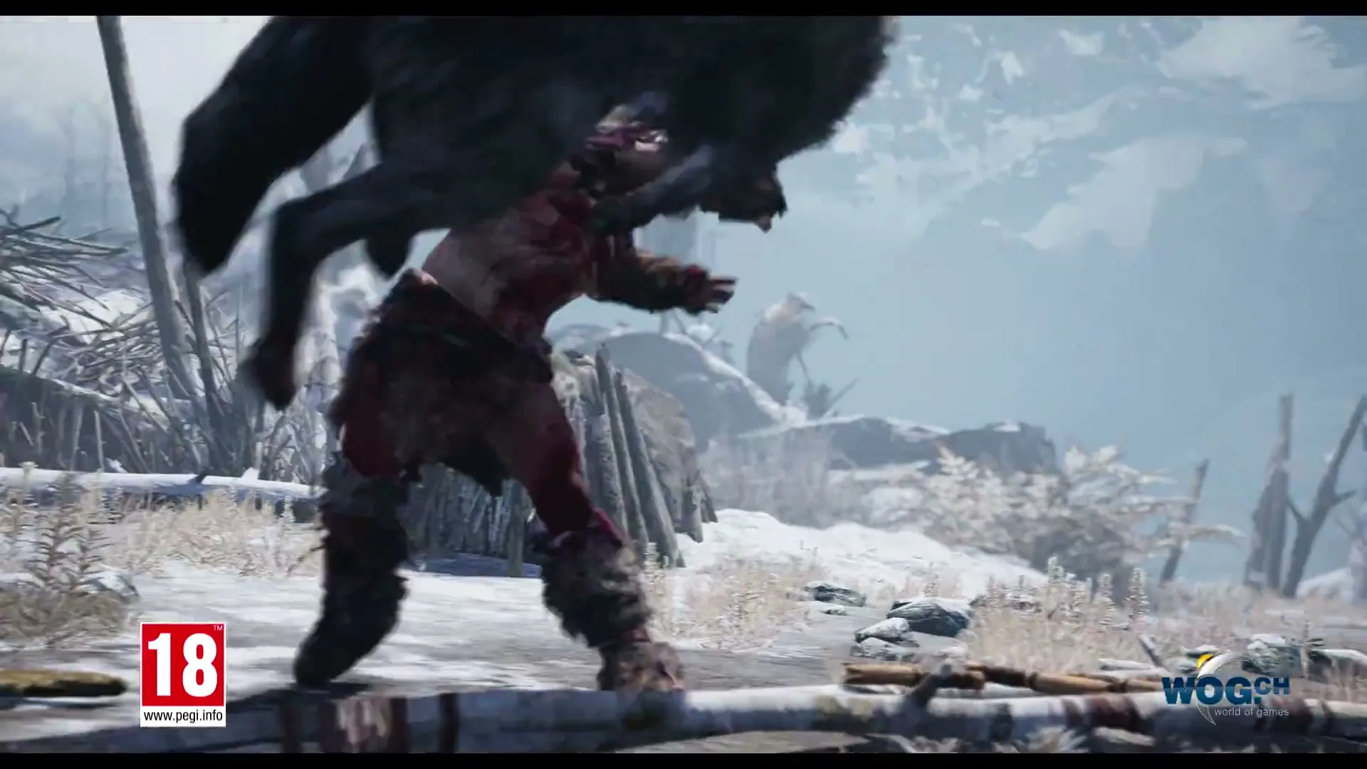 A male warrior in fur clothing fights a large grey wolf in a snowy, mountainous landscape during the day.
