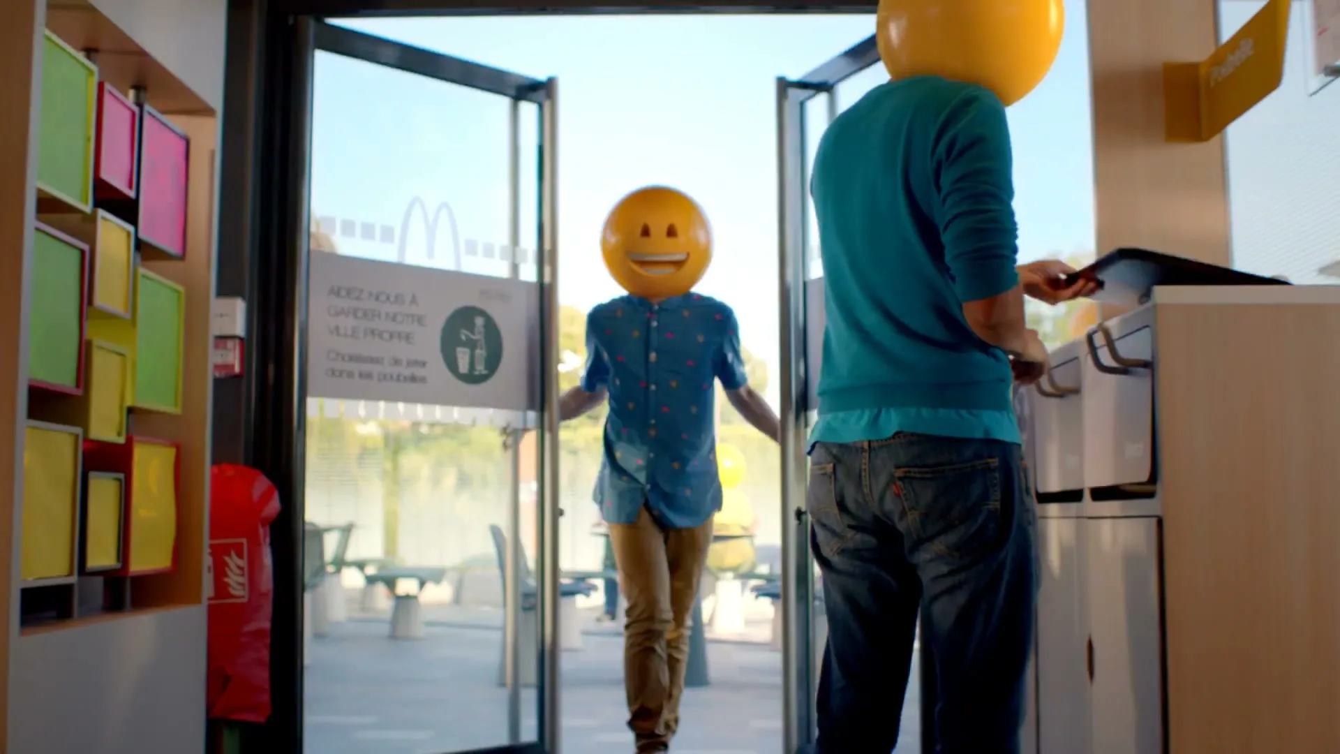 A person with an emoji head enters a McDonald's, while another person with an emoji head disposes of trash in a bin.