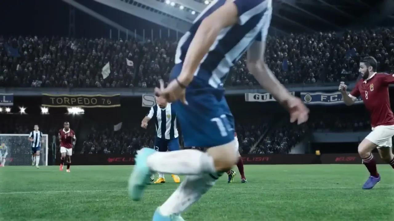 A soccer player in a striped jersey dribbles the ball past an opponent in a maroon jersey on a stadium field at night.