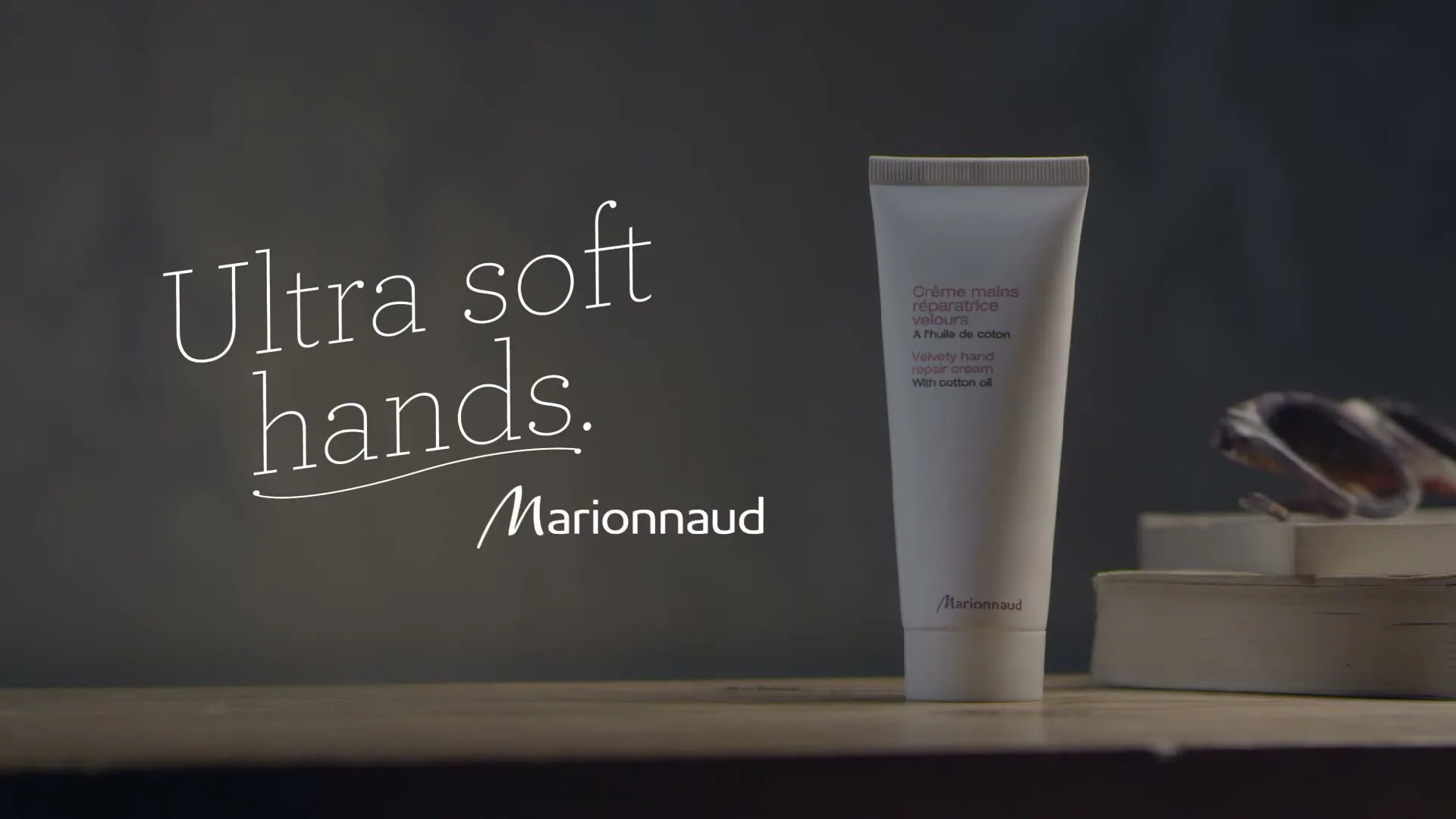 A white tube of Marionnaud hand cream stands on a wooden surface, with text "Ultra soft hands. Marionnaud" appearing on screen.