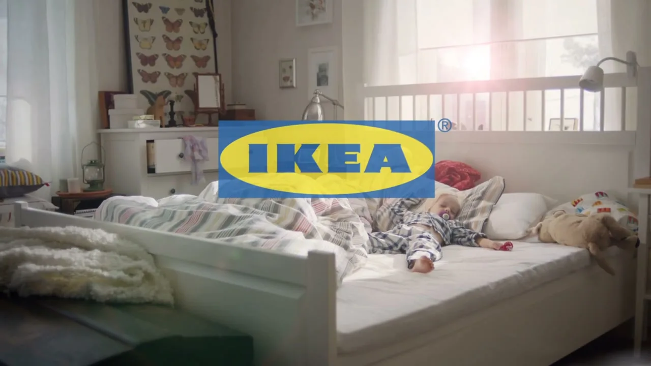 A baby in pajamas sleeps soundly on a bed in a bright bedroom, with the IKEA logo and "SLEEP TIGHT" text superimposed.