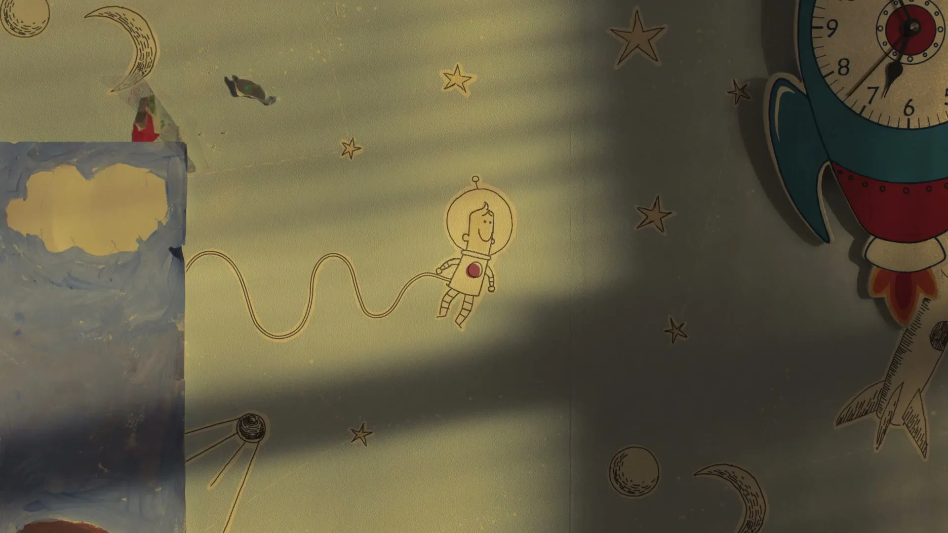 A child's bedroom wall is decorated with space-themed drawings and cutouts, including an astronaut, stars, and a rocket clock, with sunlight streaming through a window.