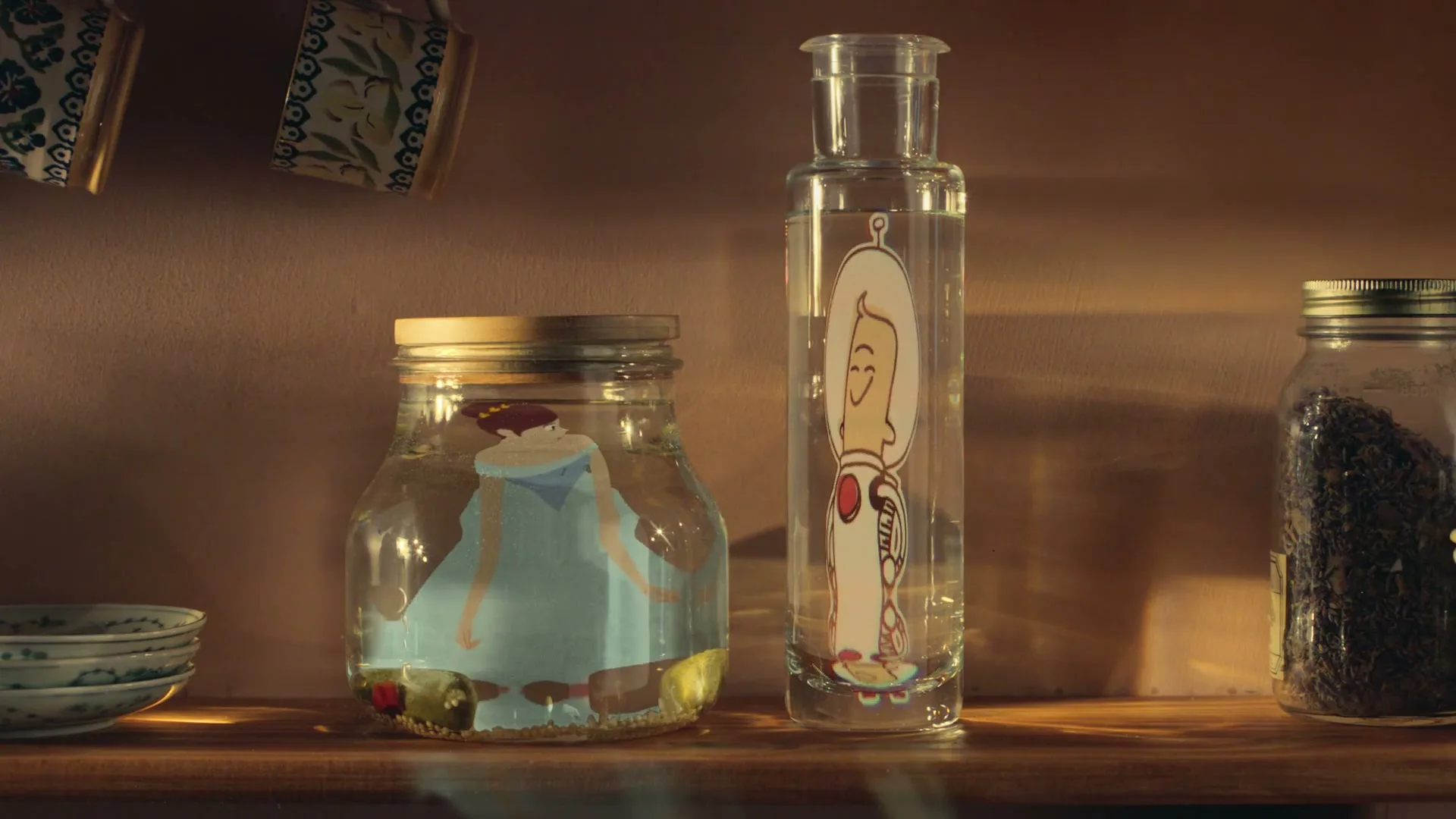 A cartoon princess and astronaut, drawn on paper, are submerged in two glass jars of water on a kitchen shelf, as the princess floats out of her jar.