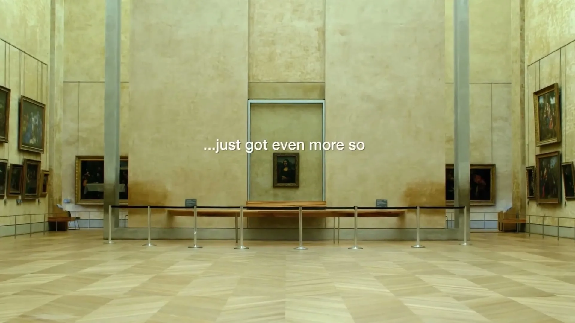 The Mona Lisa painting is displayed alone in a large, empty room at the Louvre Museum, with text appearing on screen.