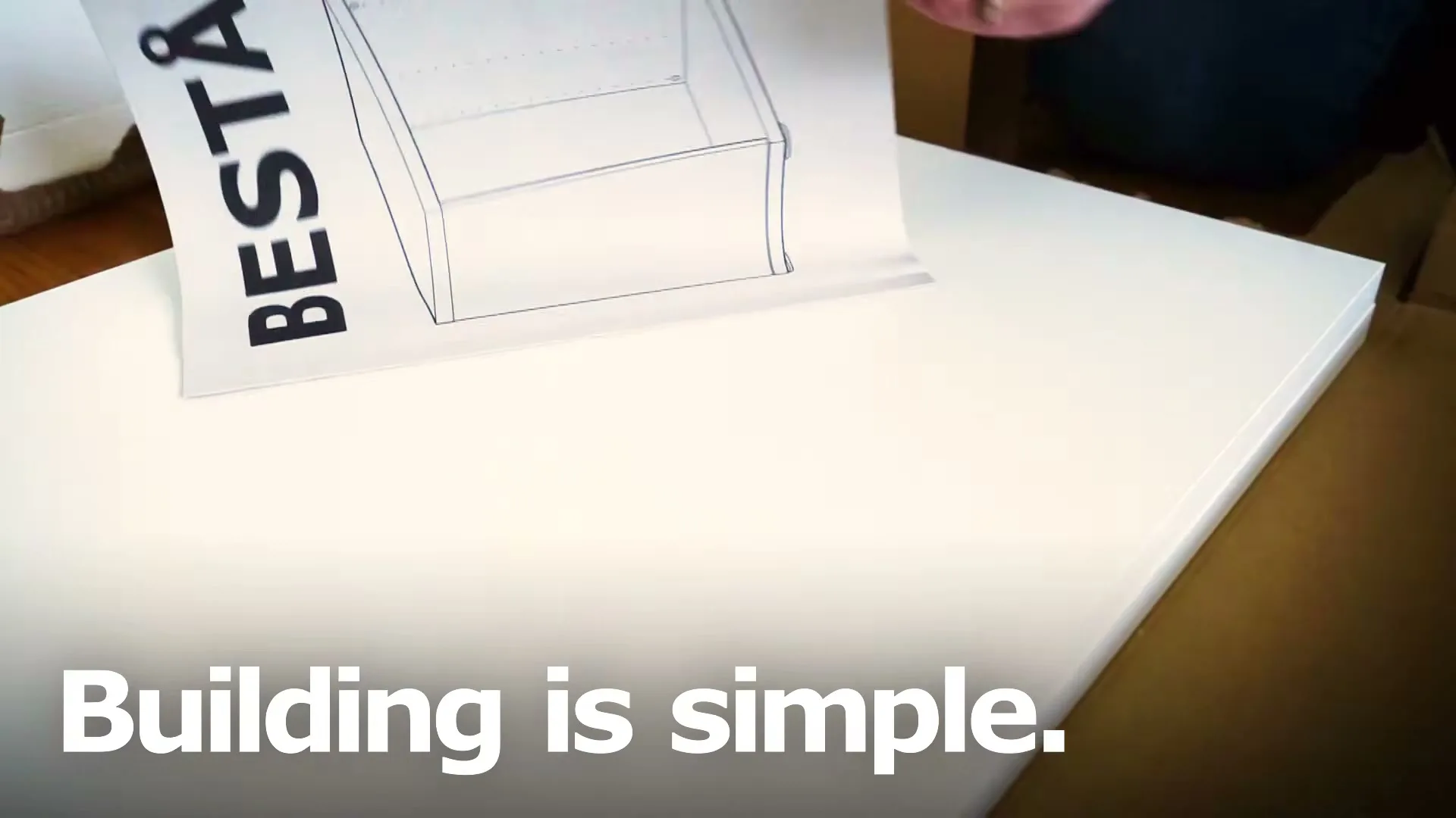 A woman's hands turn the page of an IKEA instruction manual for a "BESTÅ" furniture piece, showing assembly diagrams on a white surface.