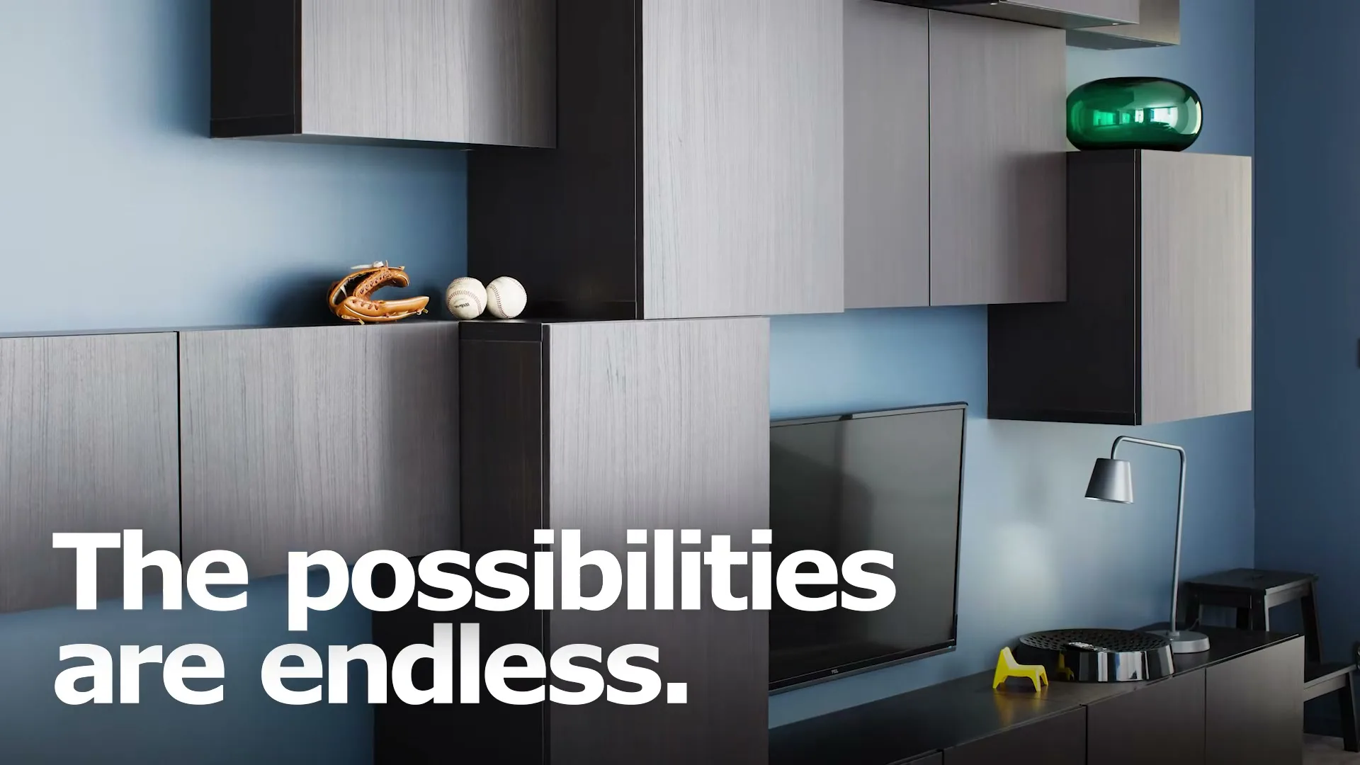 A wide shot of a modern living room with blue walls and dark grey modular shelving units, featuring a TV, a baseball glove, and a green vase.