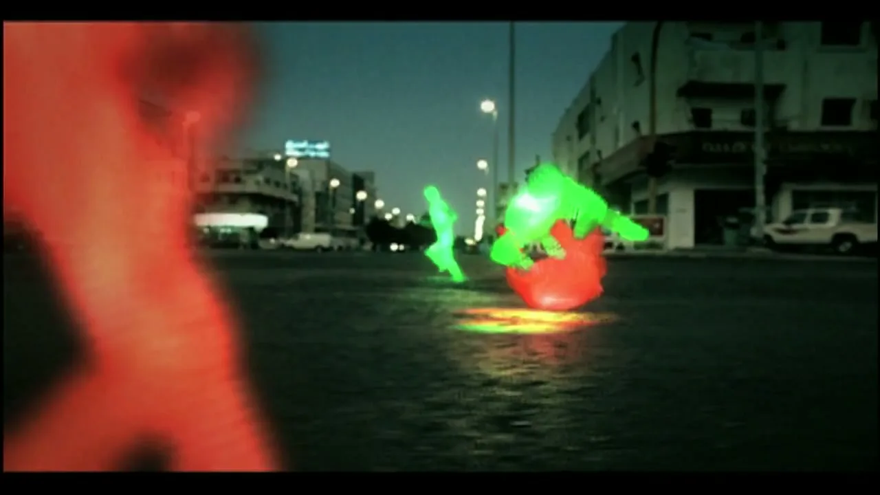Three glowing, stylized figures, one red and two green, are seen in a street at night, with the red figure in the foreground falling to the ground.
