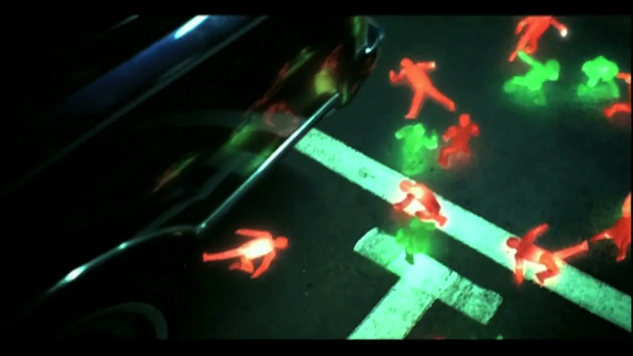 A car drives past a street with glowing red and green stick figures projected onto the asphalt at night.