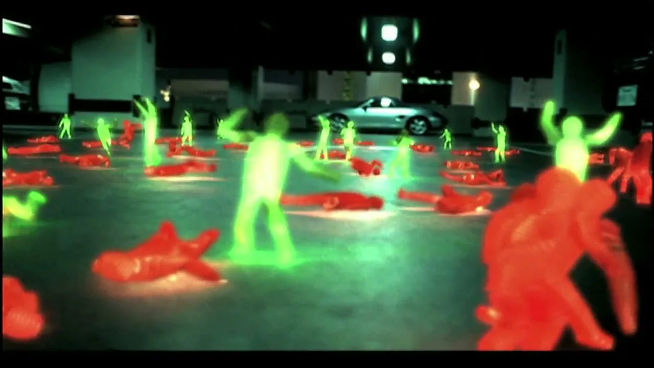 A wide shot shows many glowing green and red human figures dancing and lying on the ground in a dark parking garage at night.