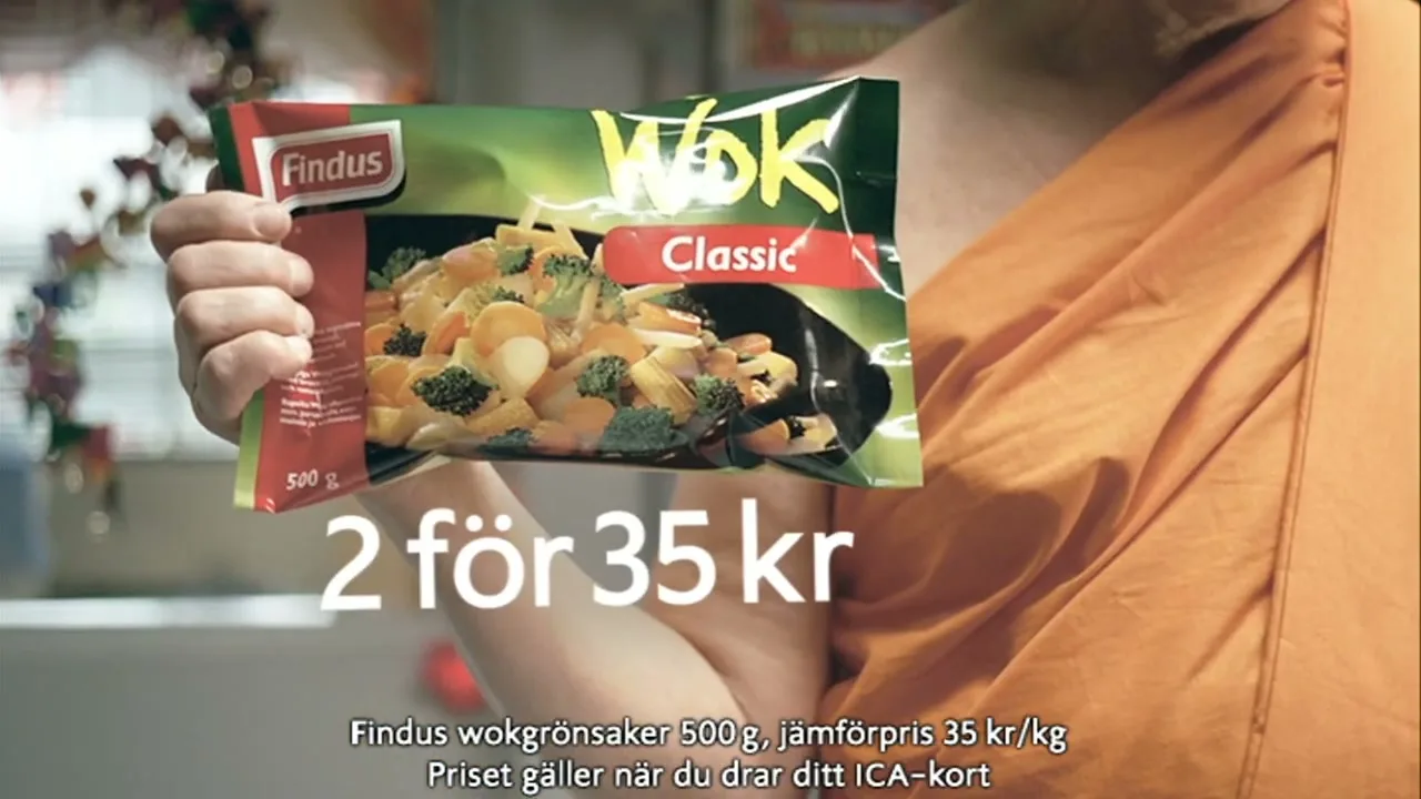 A person in an orange robe holds up a bag of frozen wok vegetables in a grocery store aisle, with text overlays showing a price offer.